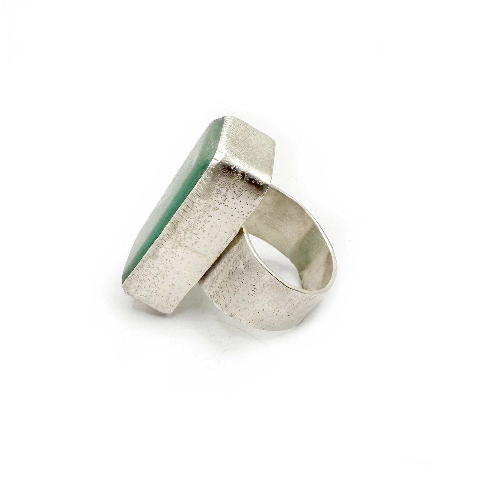 Silver ring with a green stone on a white background