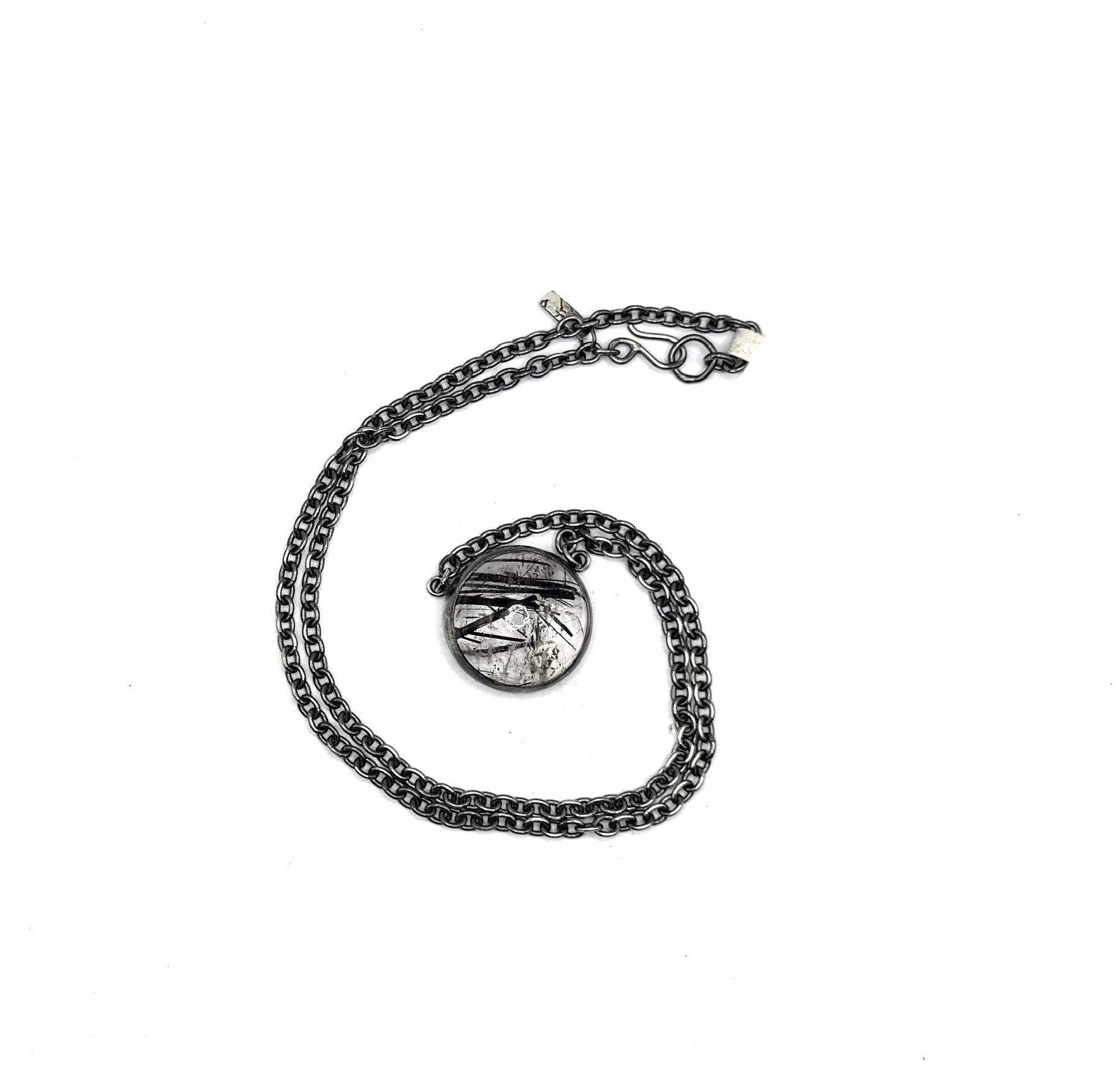 Silver chain necklace with a round pendant on a white background