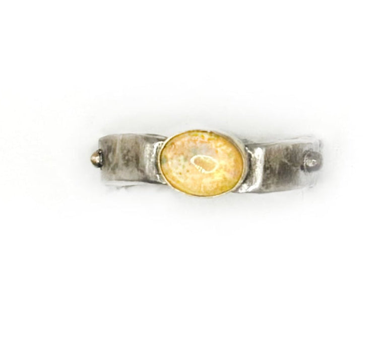 Silver ring with a yellow gemstone on a white background
