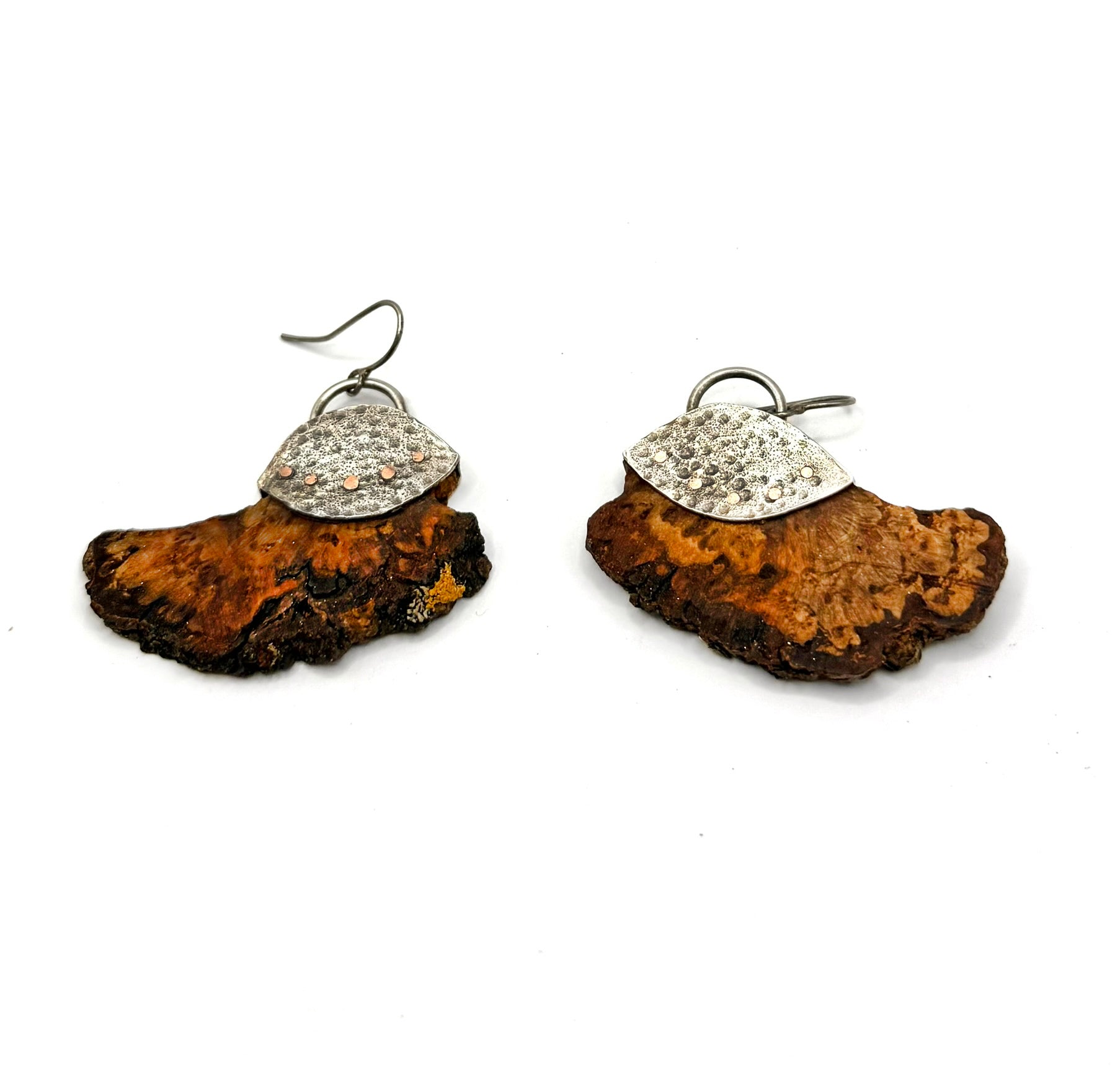 Pair of earrings with wooden base and silver top on a white background