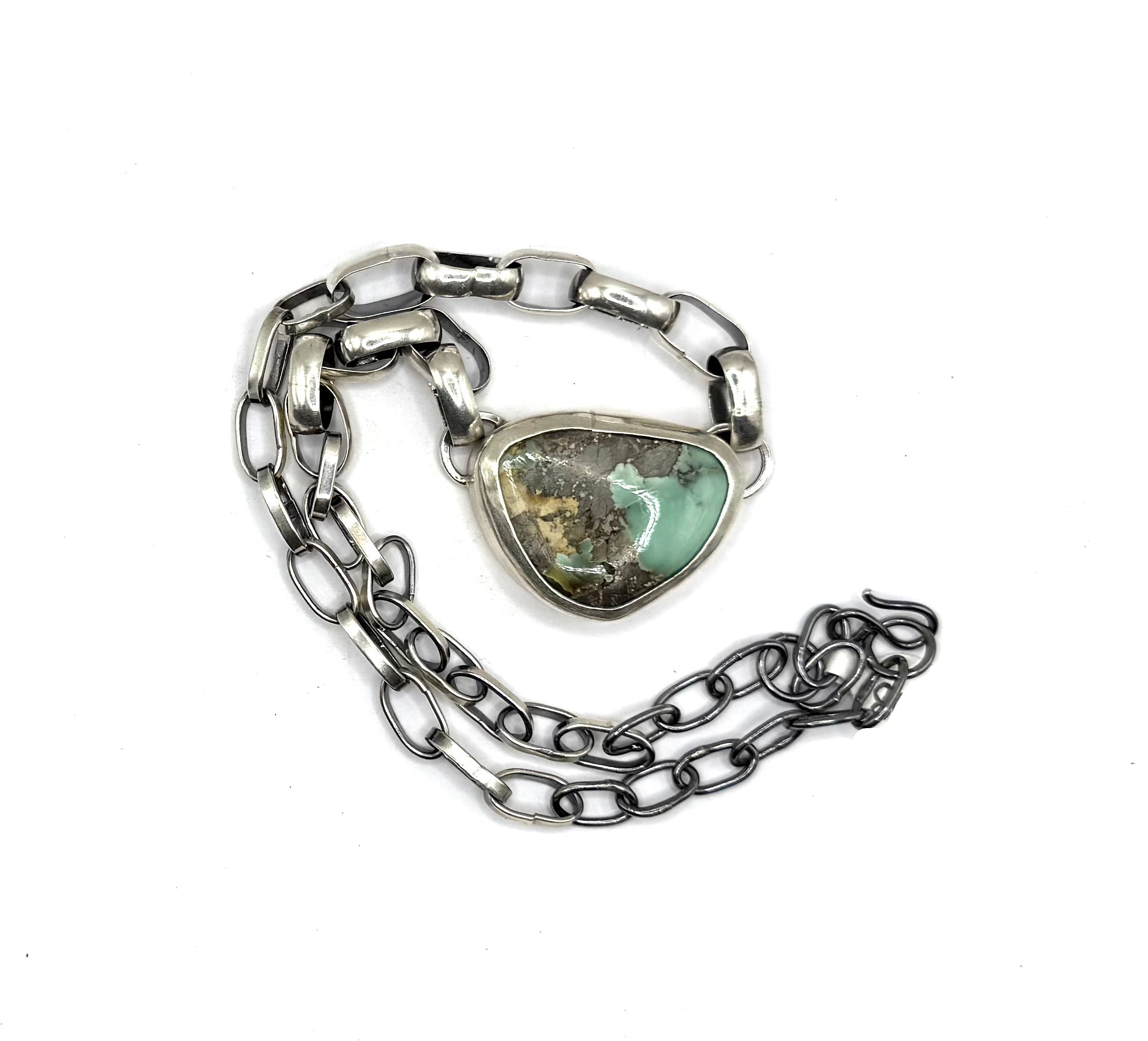 Silver chain bracelet with a heart-shaped turquoise stone on a white background