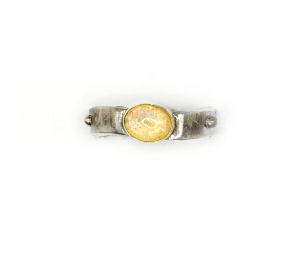 Silver ring with a yellow gemstone on a white background