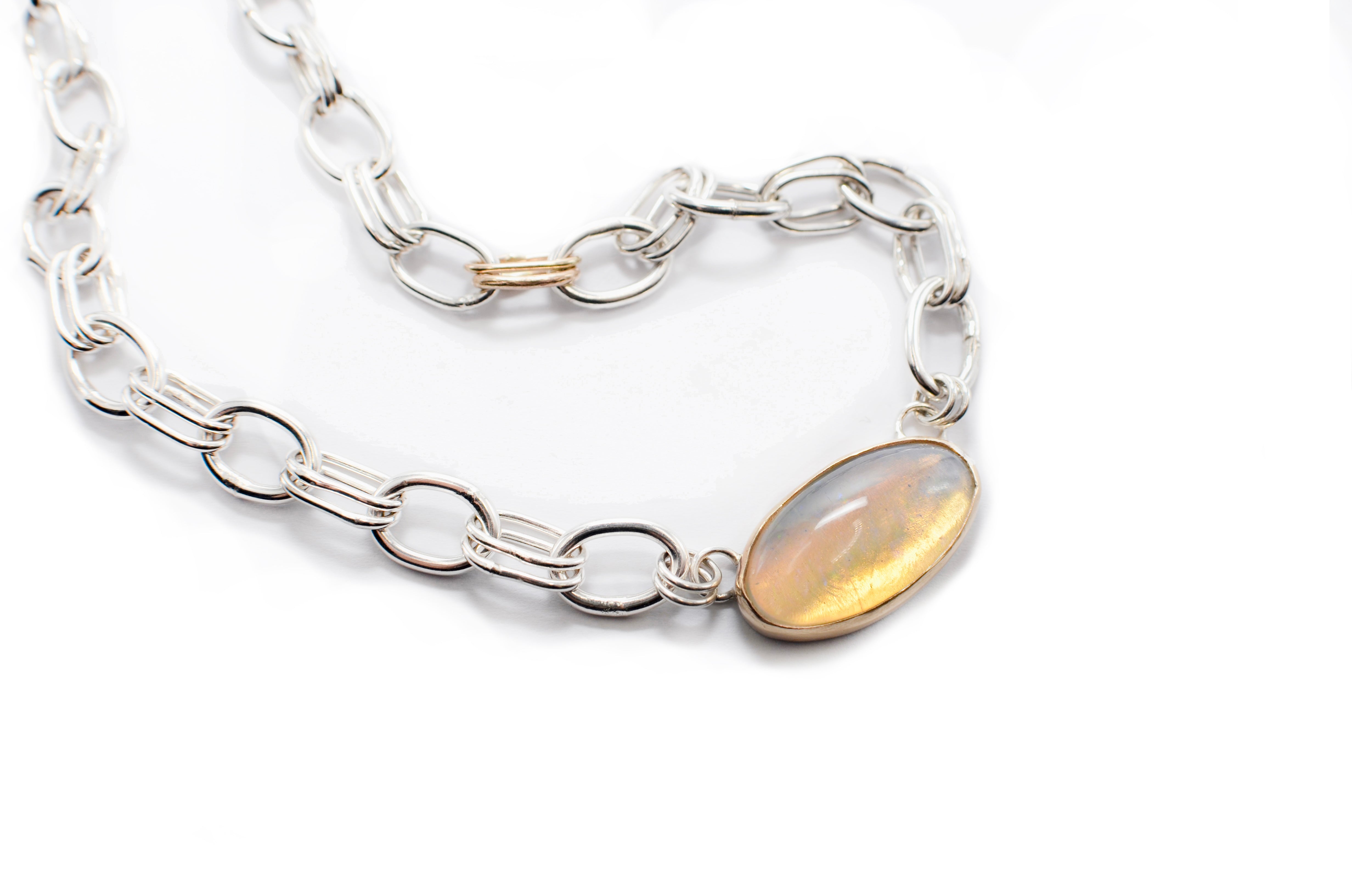 Silver chain bracelet with a central gemstone on a white background